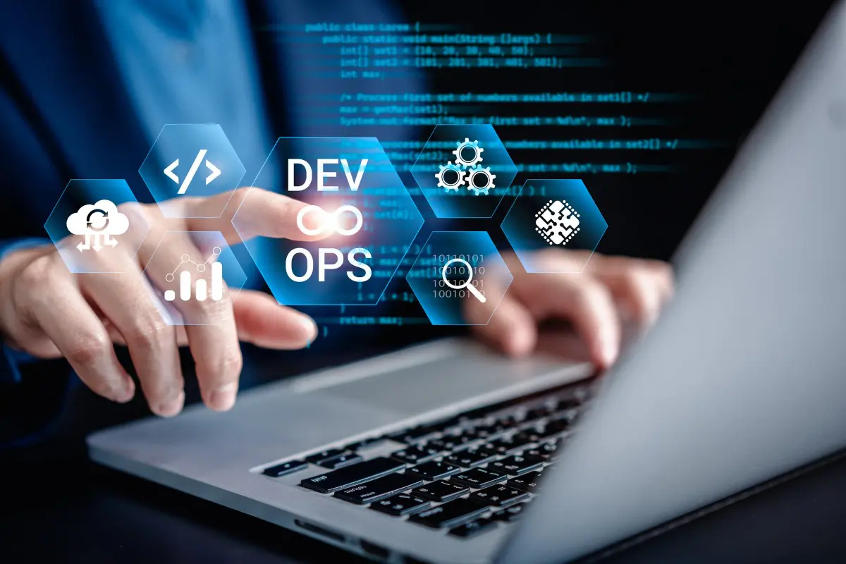 Hands typing on laptop with DevOps icons.