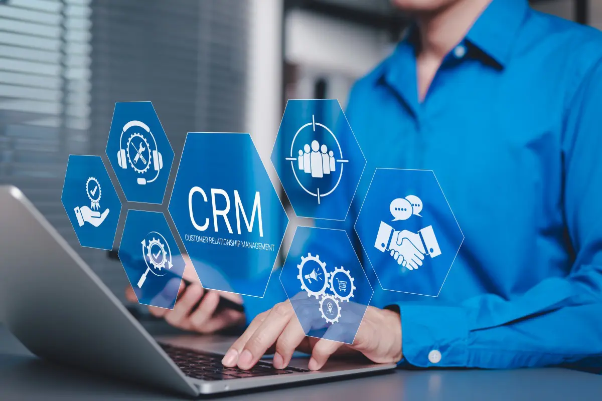 Person using laptop with CRM graphics displayed.