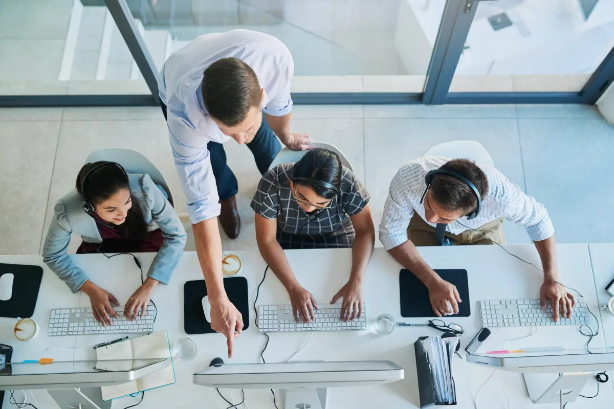 Team collaborating at office workstations from above.