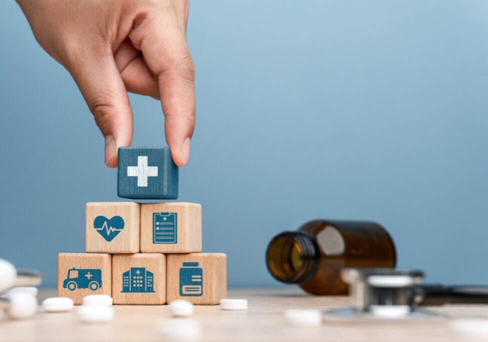 Hand stacking healthcare-themed wooden blocks.